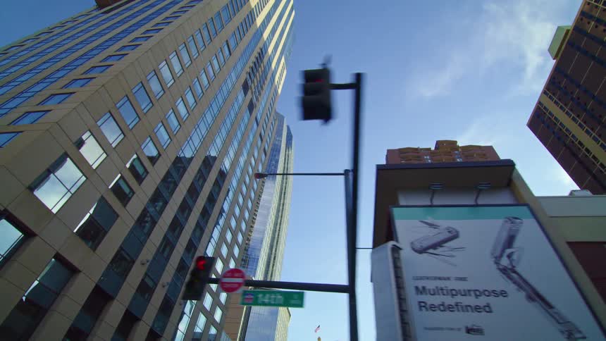 A city with buildings traffic lights signs and trees with the sky and clouds above