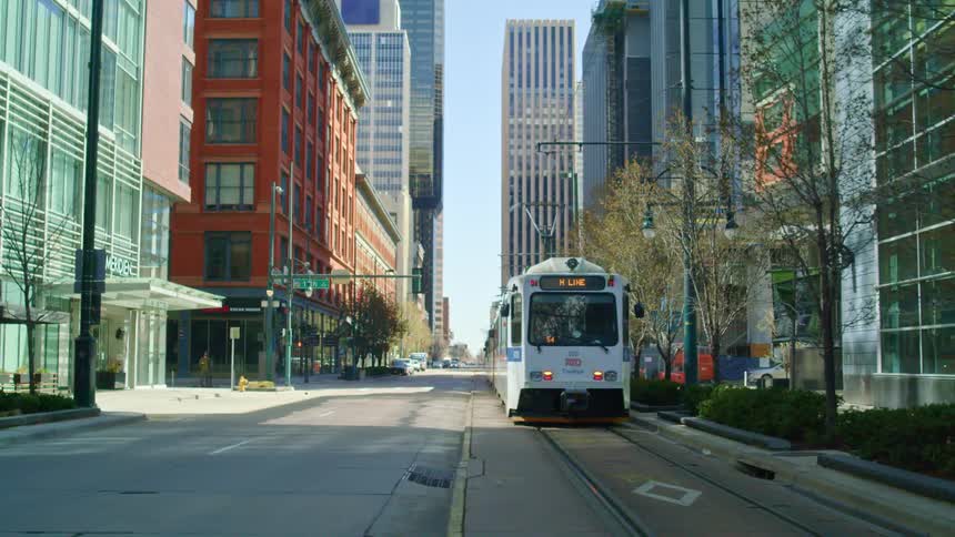 An empty white tram goes along metal tracks in the road through empty streets during lockdown in the city
