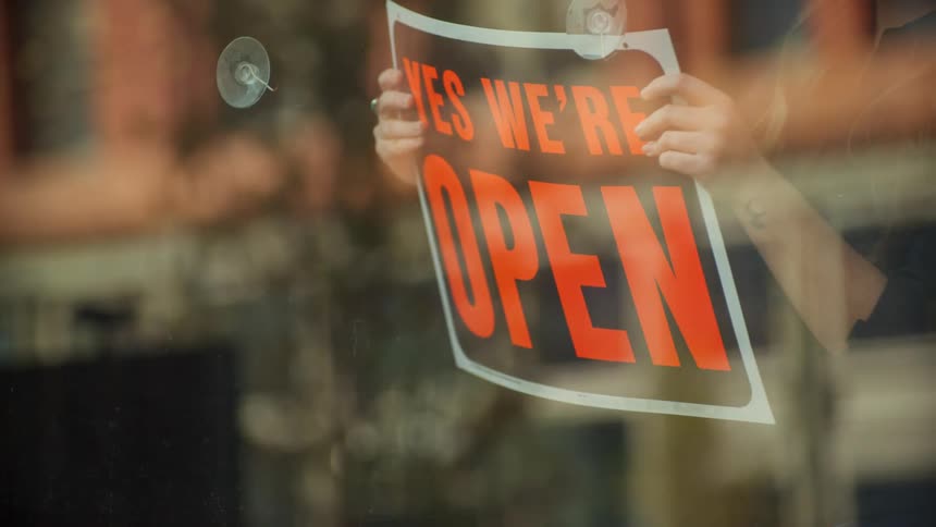 A woman turns over a sign in a store window