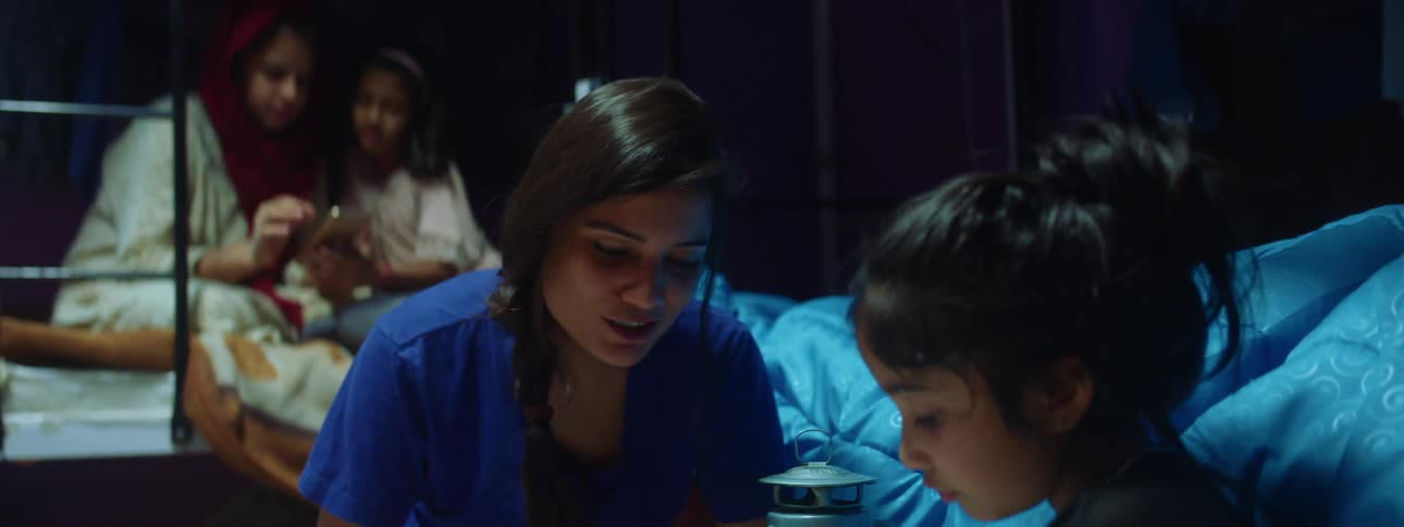 Two women help their children do school work