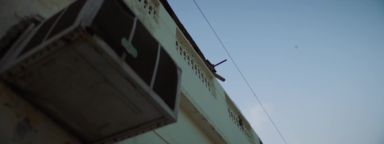 An airplane flies high over a building on a sunny day
