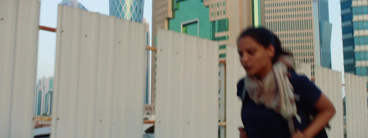 A teenage girl quickly walks down a sidewalk in a downtown area