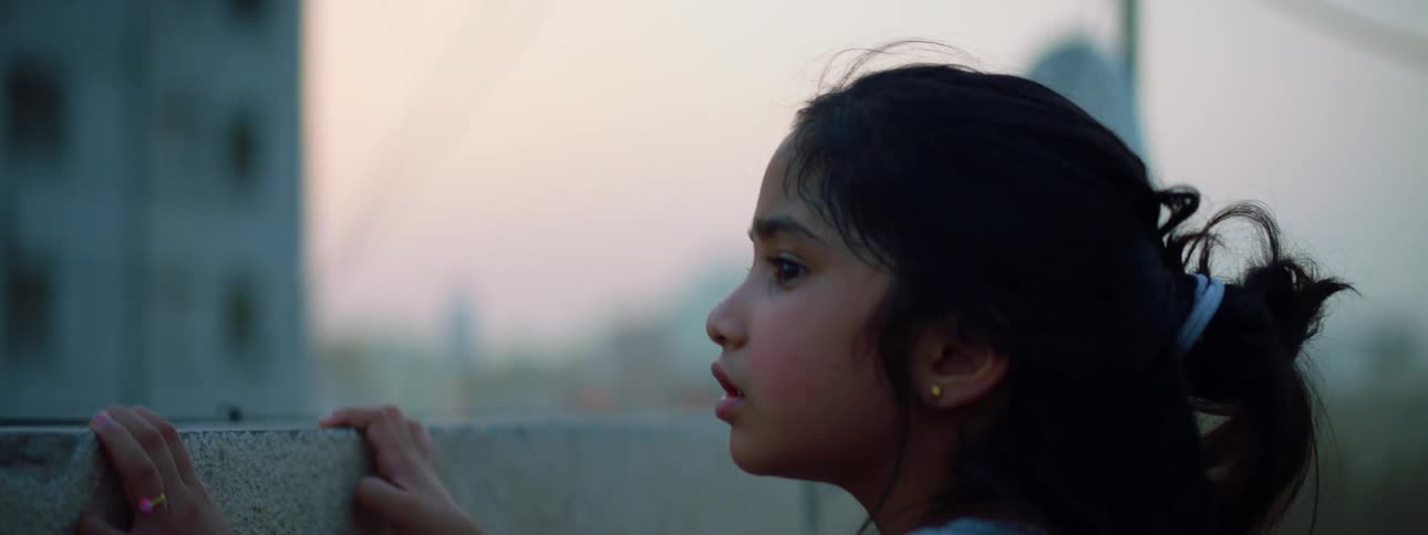 A little girl stands outside and looks all around