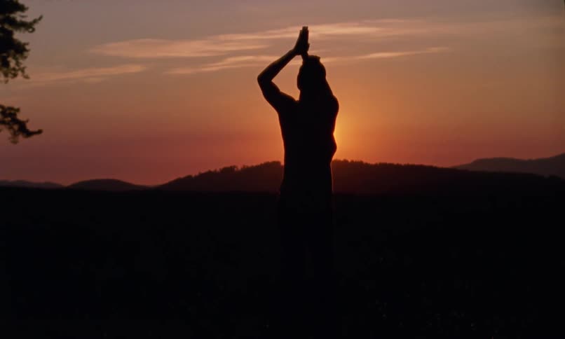 A man is stretching outdoors at dusk