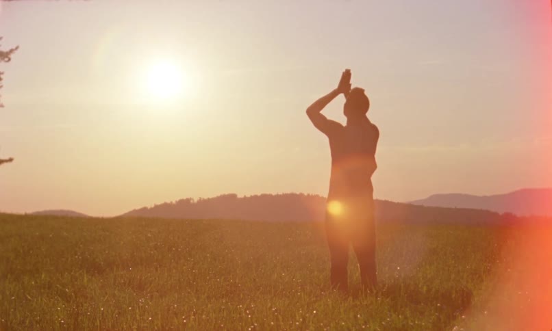 A man is stretching outdoors at dusk
