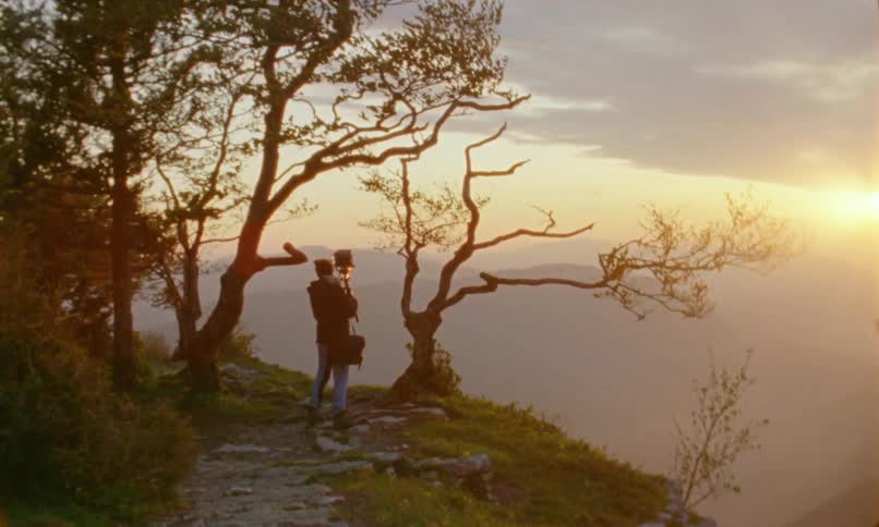 A man sets up a camera on a windy mountain