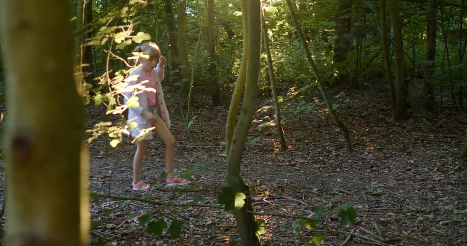Blonde girl walks through forest and sun glare