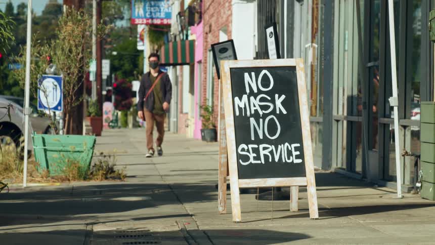 A teenager walks down a city street filled with stores