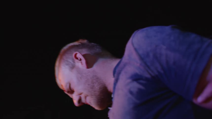 A man with a bloody forehead being detained by police officers with a police car in the background
