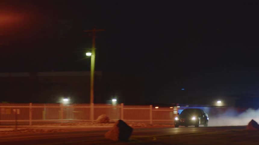 Two police cars with their lights on chase another car down a road