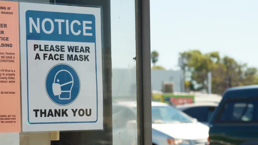 Man walks down the street wearing a mask as vehicles travel nearby