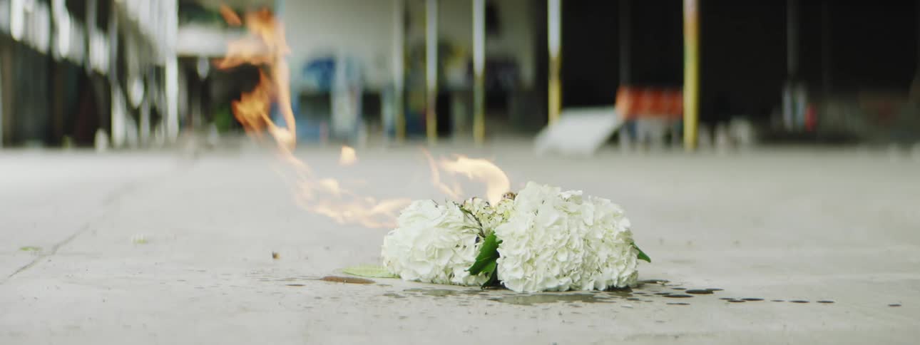 A bouquet of flowers burn on the sidewalk