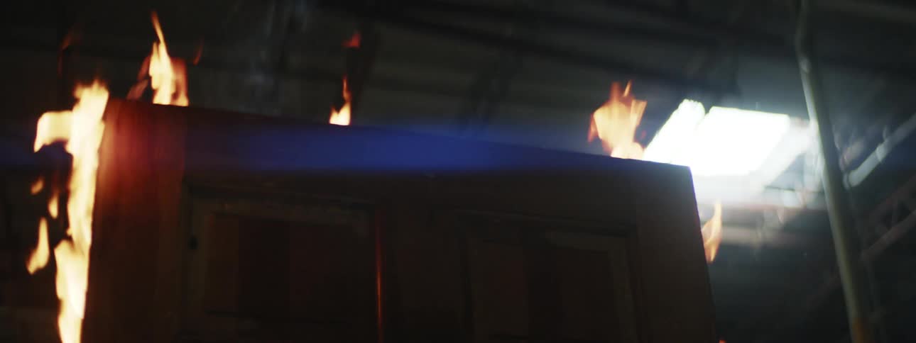 Fire burns wooden panel releasing smoke toward skylight