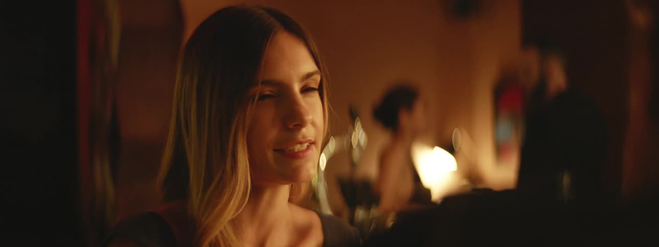 A woman sits at a bar and talks with someone