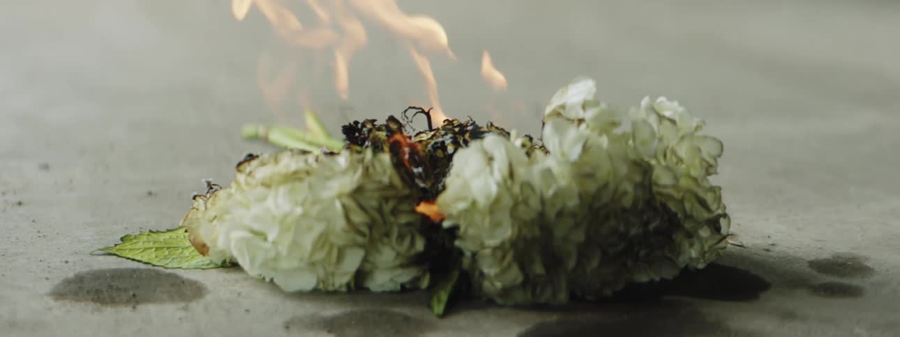 A fire burns flowers on concrete