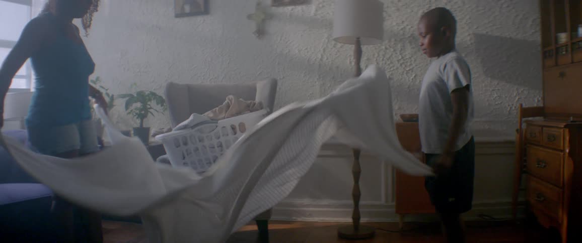 A boy helps shake out a white sheet