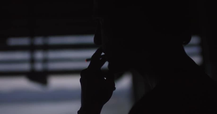 A standing man smokes a cigarette