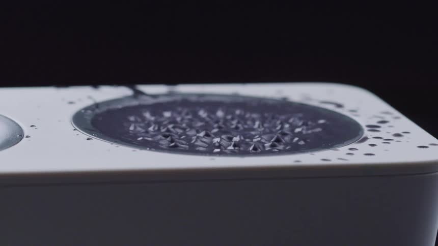 Grey liquid over a speaker vibrates with the sound waves