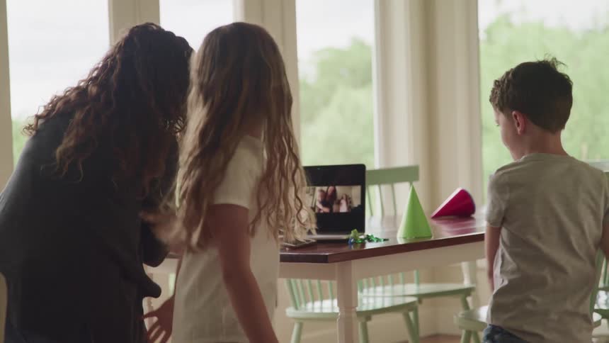 A woman and children dance on a video conference party