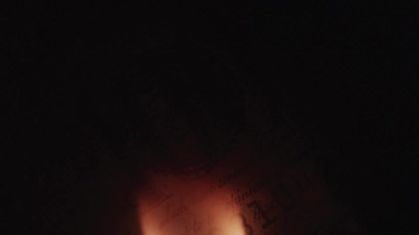 A flame burns in front of cash