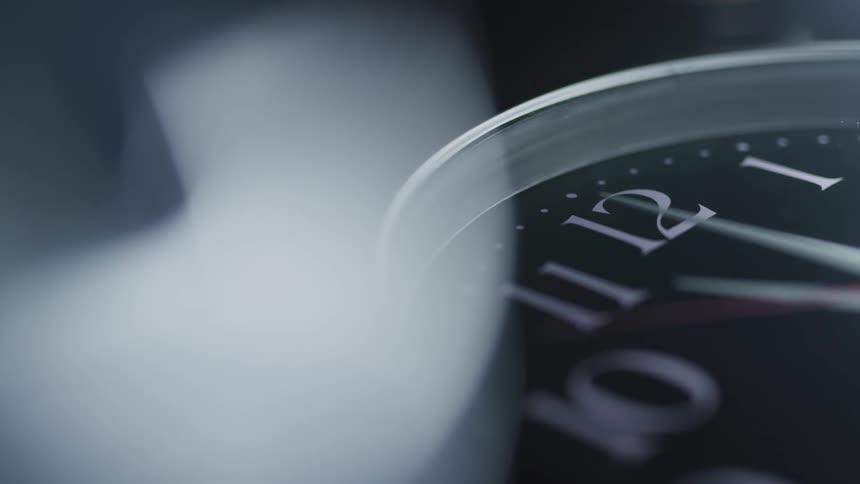 An analog clock with a red second hand moving