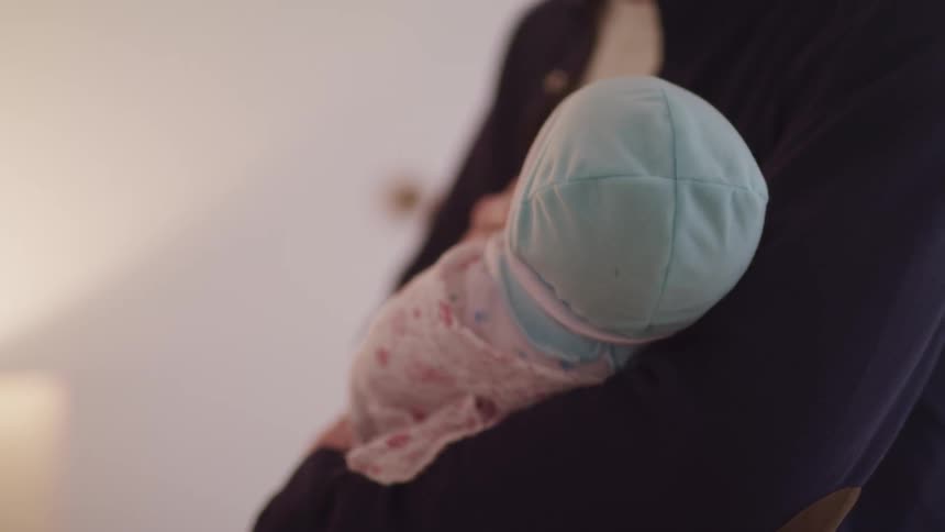 Mother gently holding newborn baby in her arms at home
