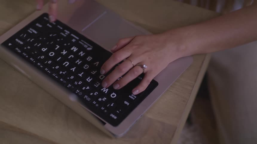 A woman is typing on a laptop indoors