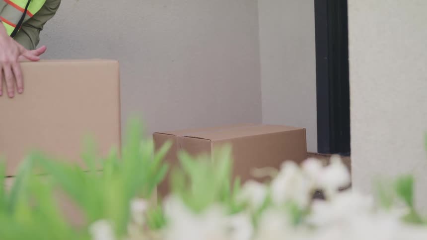 A delivery driver stacks boxes on a customers front porch