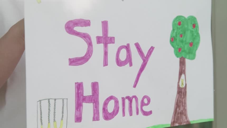 Sign with a stay home instruction is held in a window