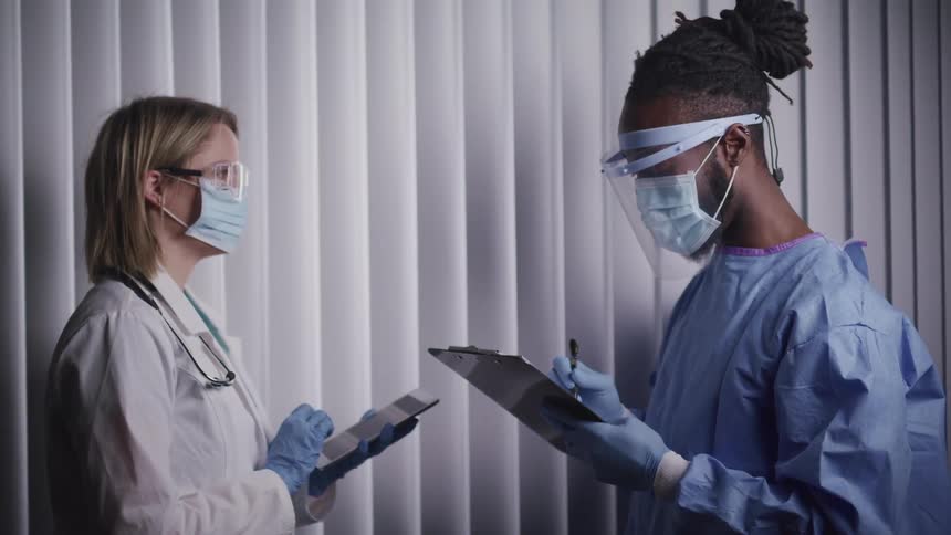 Nurse holds a clipboard while talking with a doctor holding a tablet