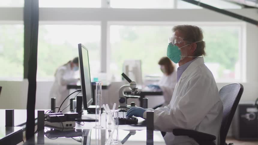 Three doctors are in a lab using equipment