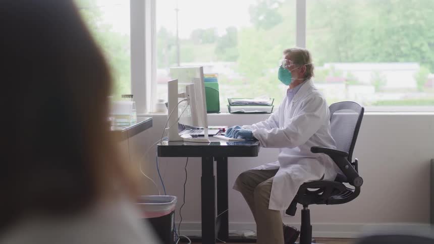 A scientist is working at the computer in the lab