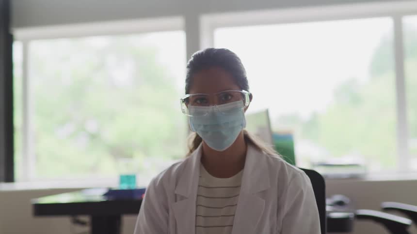 A lab technician in a face mask is sitting