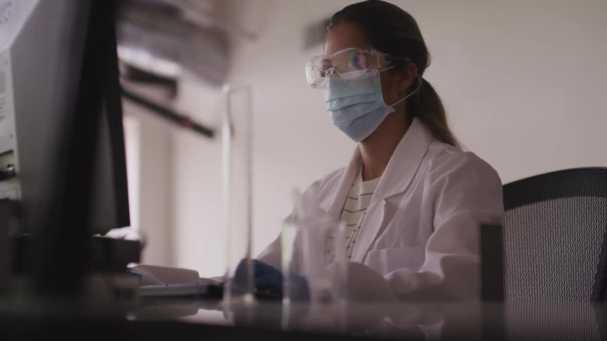 A woman is sitting at a computer working in a lab
