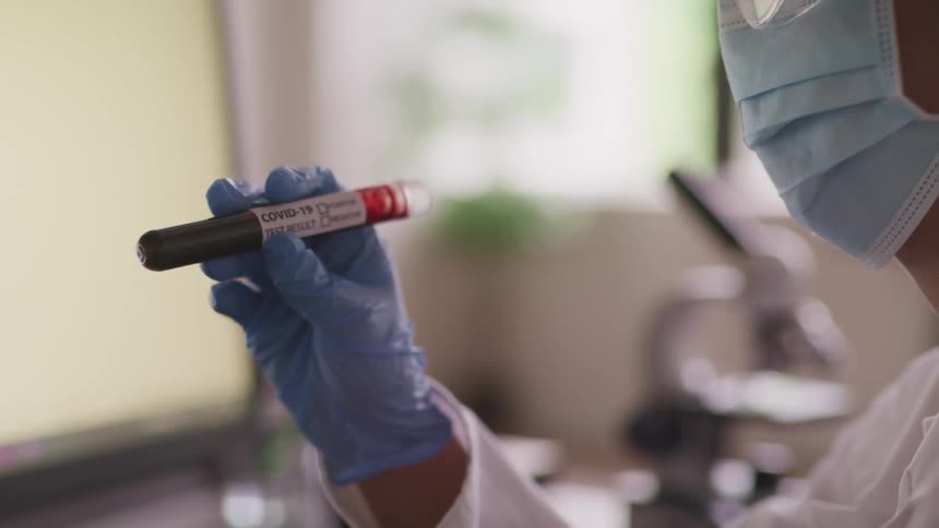 A woman holds a test tube and looks at it