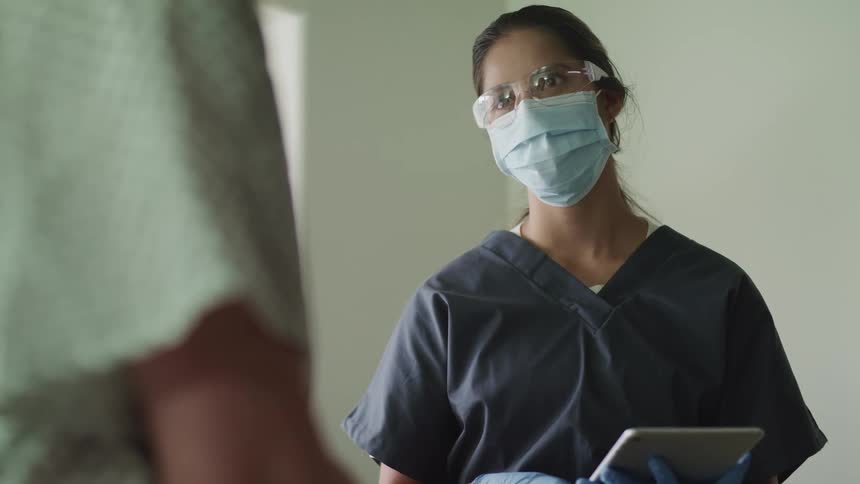 A nurse talks to a patient in a clinic as she uses a tablet