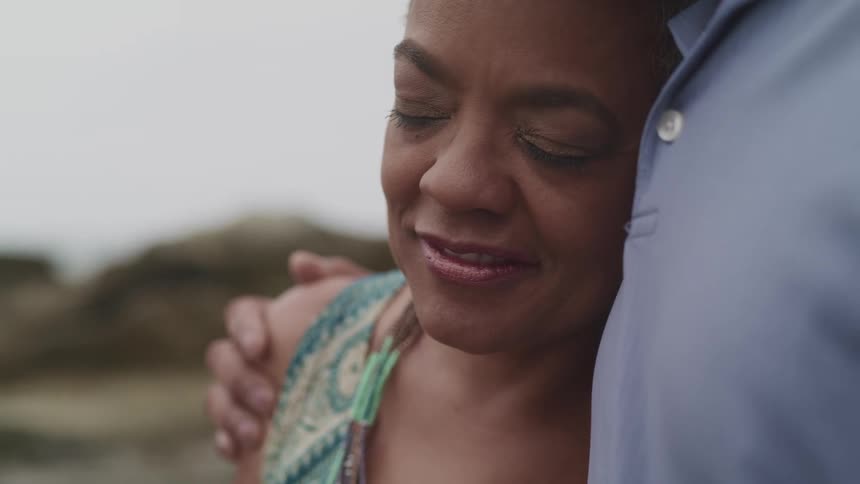 A man has his arm around his wife and she smiles with her eyes closed