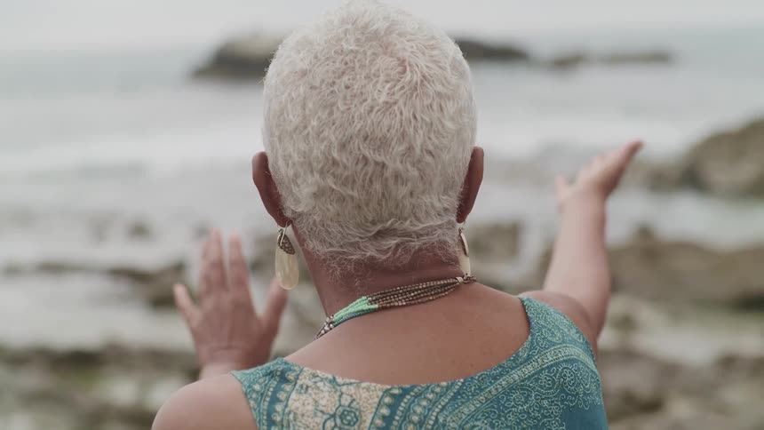 A woman does tai chi on the beach near the shore