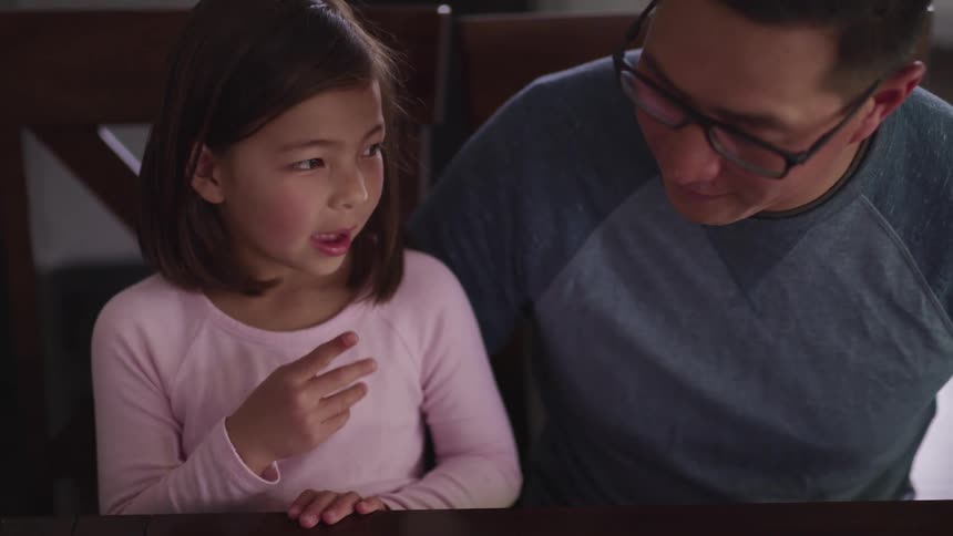 A man sits next to his little girl and listens as she talks to him