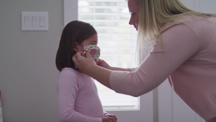 A woman puts a mask on her daughter