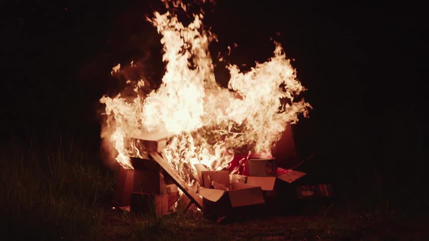 Boxes and wood burning outside at night