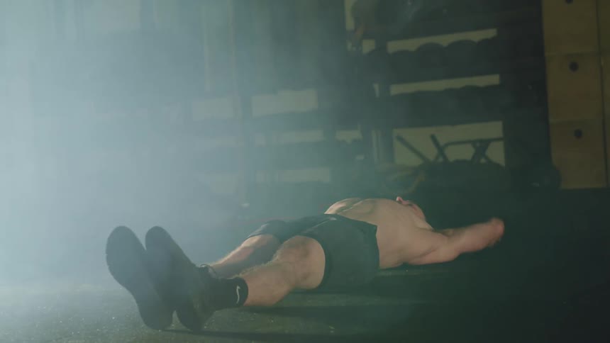 Man lays on the floor and touches his hands to his toes in the gym