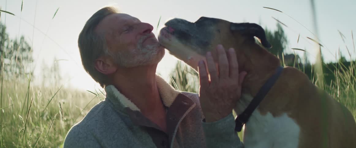 A dog is licking a mans face