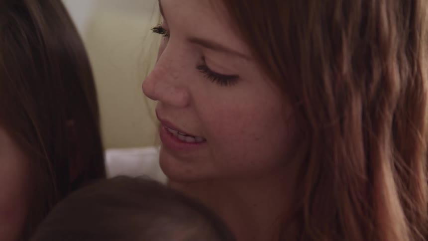 Woman holds a baby on her lap as she sits close to a young girl