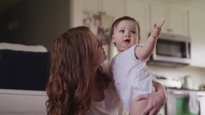 A woman is talking with a baby in the kitchen