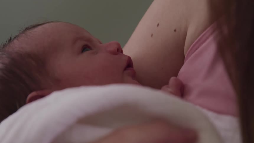 A woman cradles a baby who is wrapped in a blanket