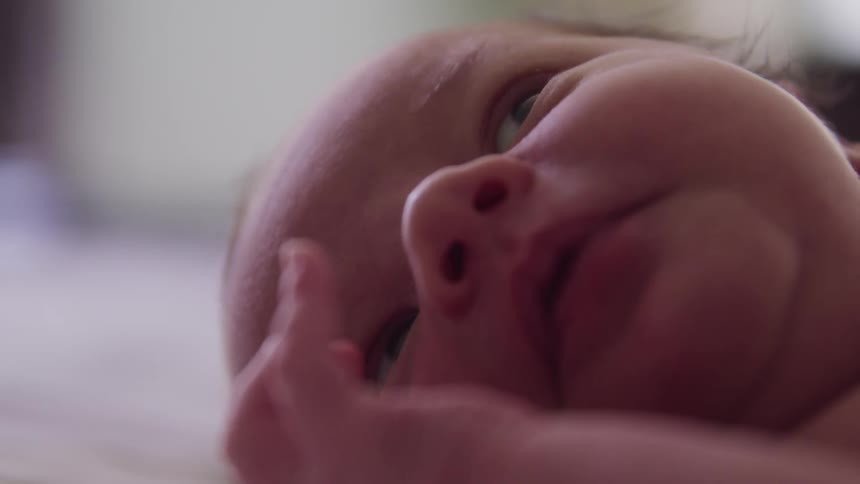 Baby smiles and sticks out tongue while lying down