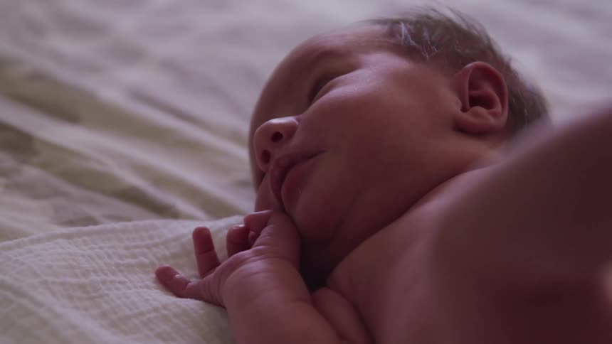 A newborn moves around in the crib