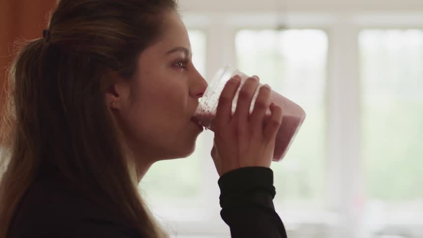 A teenager drinks a smoothie at home