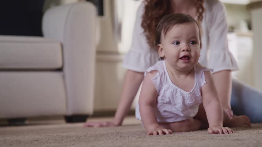 Mother sits in the floor of the living room with her baby daughter